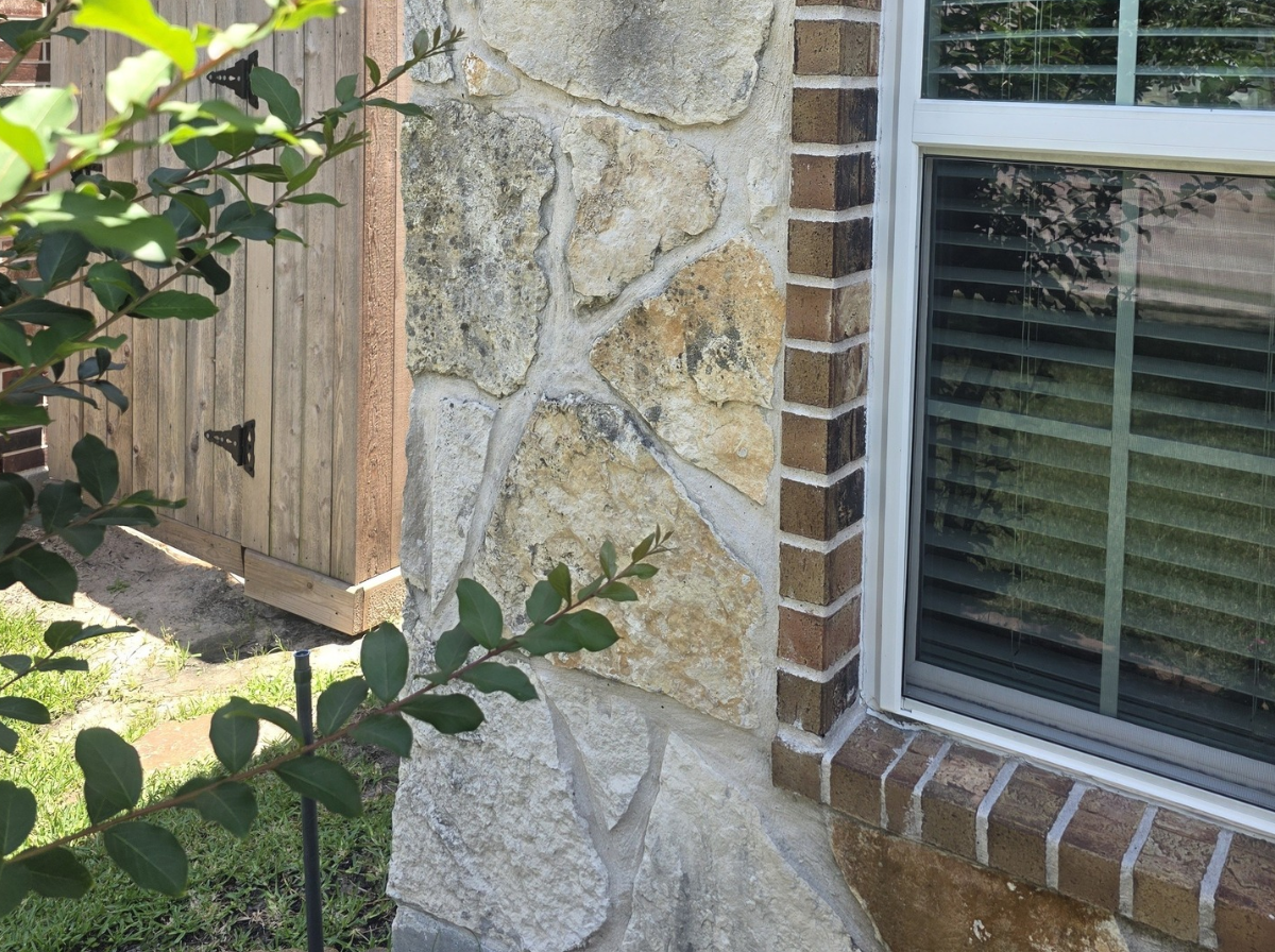 Clean natural limestone stone wall on home in Lakewood Forest Cypress TX after professional soft wash cleaning restored the vibrant gold and tan stone color
