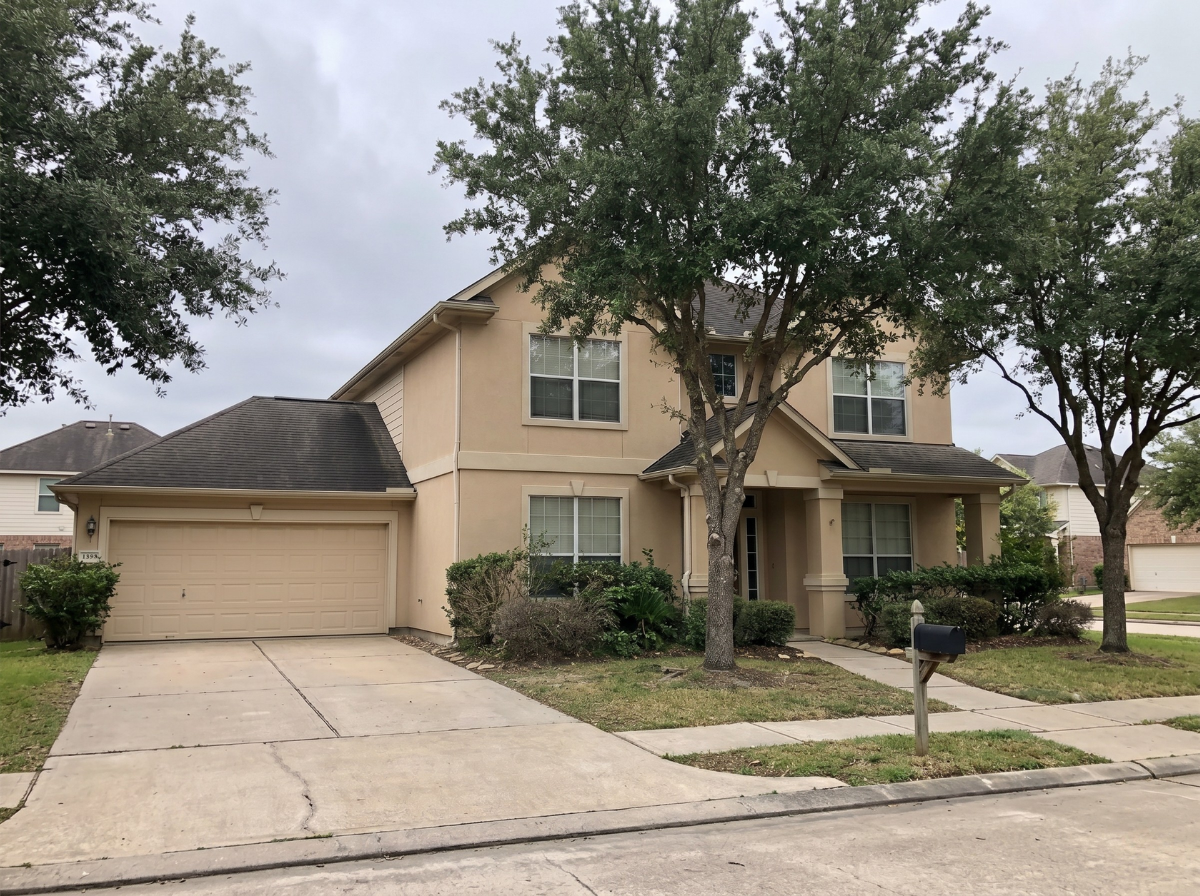 Clean two-story beige stucco home in Coles Crossing Cypress TX after professional soft wash house washing refreshed the full exterior to original color